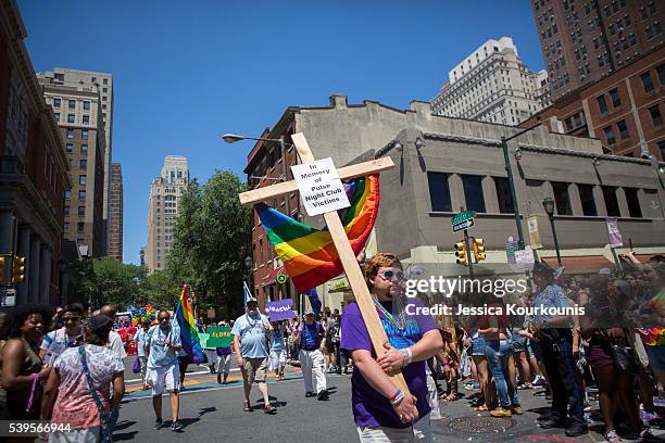 Austin Ellis, a member of Metropolitan Community Church, carries a cross with a sign in memory of the victims of the Pulse nightclub shooting as he...
