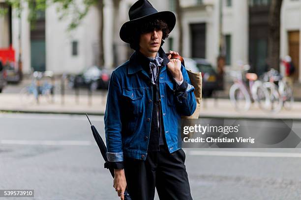 Guest wearing a denim jacket, black pants and hat outside Christopher Raeburn during The London Collections Men SS17 on June 12, 2016 in London,...