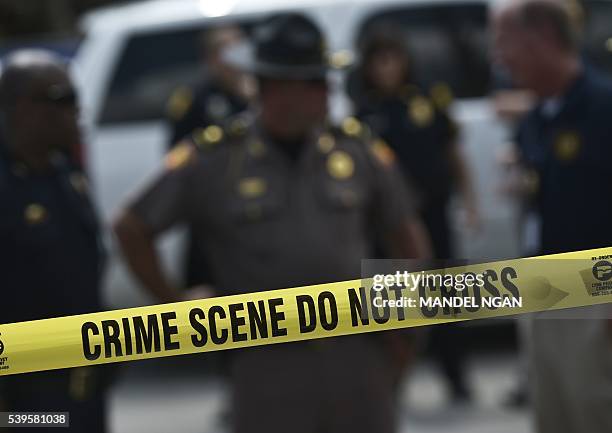 Police stand behind a crime scene tape near the mass shooting at the Pulse nightclub on in Orlando, Florida on June 12, 2016. A somber President...