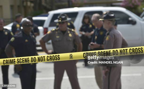 Police stand behind a crime scene tape near the mass shooting at the Pulse nightclub on in Orlando, Florida on June 12, 2016. A somber President...