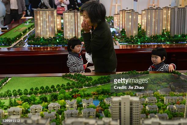 Two children plays and a woman looks a property model in a real estate exhibition in Jiaxing, Zhejiang province, China on 18th April. China's annual...