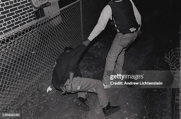 During the height of the crack epidemic in Bridgeport, CT, a narcotics officer hauls a prisoner arrested in a raid on crack hose off to a waiting...