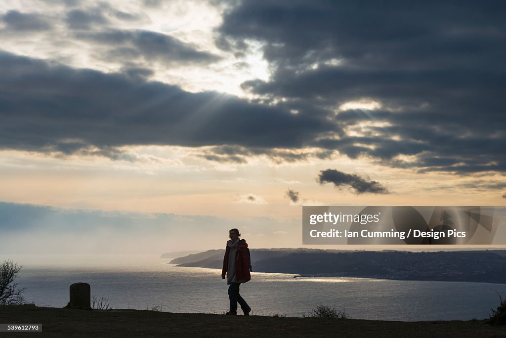 Woman walking near the top of Golden Cap with Lyme Regis behind, Jurassic Coast