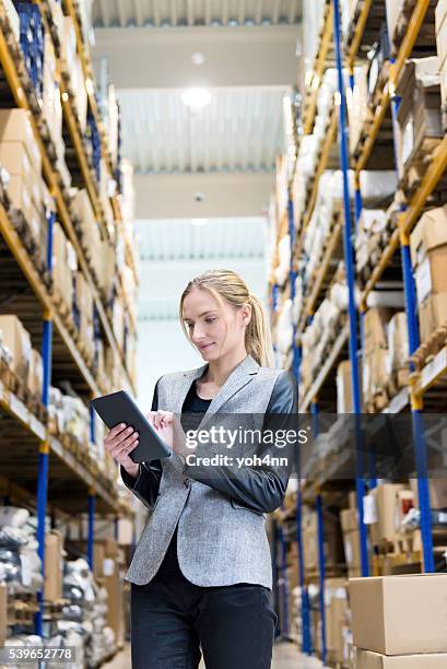 concentrado mujer trabajando con tableta en almacén de distribución - superalmacén fotografías e imágenes de stock