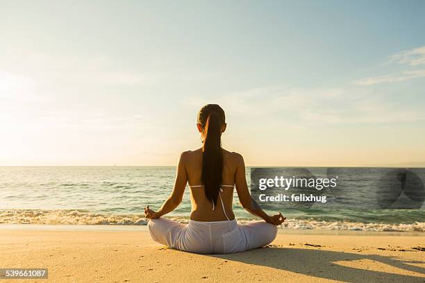 woman meditating on beach - beach yoga stock-fotos und bilder