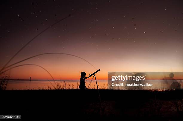 silhouette of boy looking at stars through telescope - discovery stock pictures, royalty-free photos & images