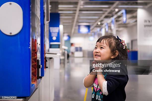 girl standing by vending machine in corridor and smiling - asian ceiling stock-fotos und bilder