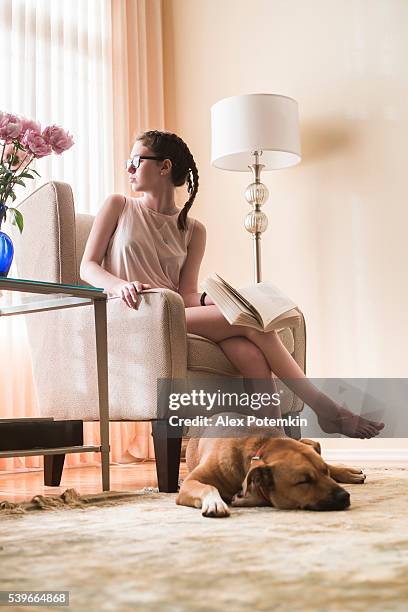 teenager girl reads book in living room with dog nearby - monochrome clothing stock pictures, royalty-free photos & images