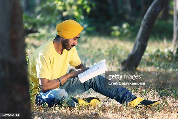 young man reading a book - sikhism stock pictures, royalty-free photos & images