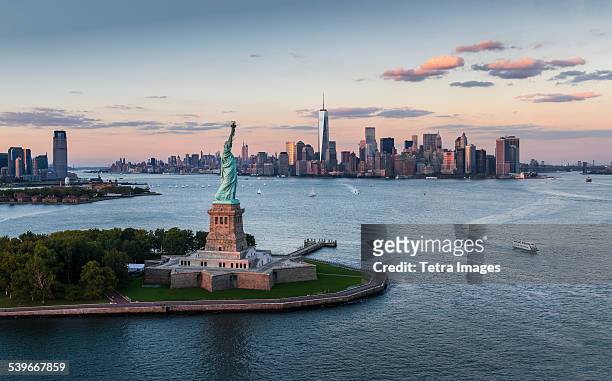 usa, new york state, new york city, aerial view of city with statue of liberty at sunset - insel liberty island stock-fotos und bilder