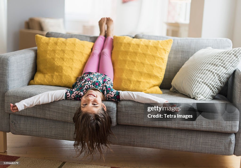 USA, New Jersey, Girl (6-7) lying upside down on sofa