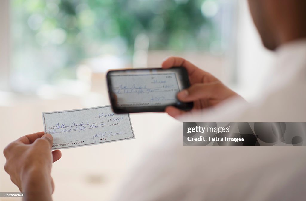 USA, New Jersey, Man taking photo of banking check with cell phone