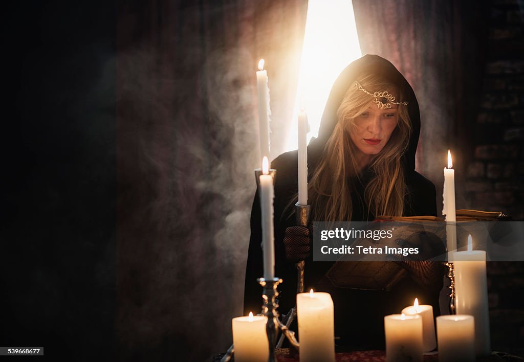 USA, New Jersey, Sorceress reading book in dark room