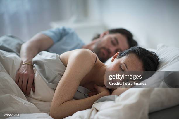 usa, new jersey, couple sleeping together in bed at night - man and woman cuddling in bed stock-fotos und bilder