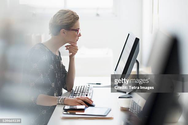 usa, new jersey, side view of business woman working on desktop pc in office - input device stock-fotos und bilder