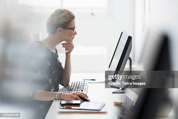 usa, new jersey, side view of business woman working on desktop pc in office - invoerapparaat stockfoto's en -beelden