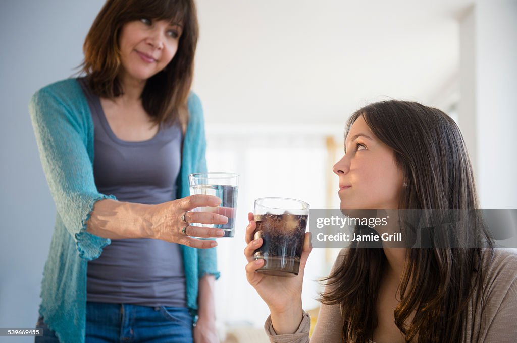 USA, New Jersey, Mom encouraging teenage girl (14-15) to drink mineral water