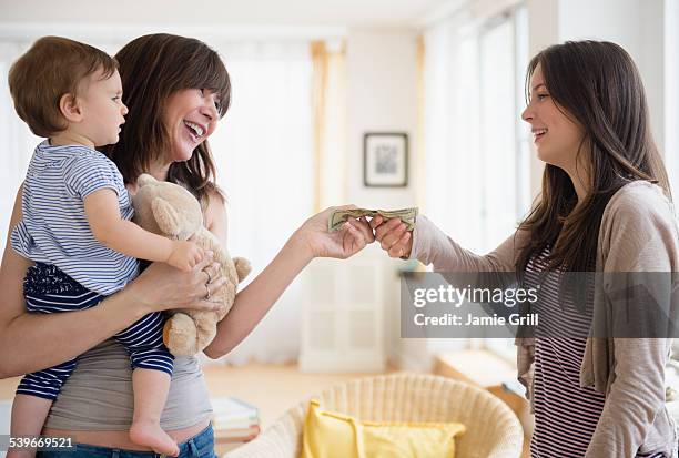 usa, new jersey, woman paying teenage nanny (14-15) for taking care of her son (12-17 months) - babysitter stock pictures, royalty-free photos & images