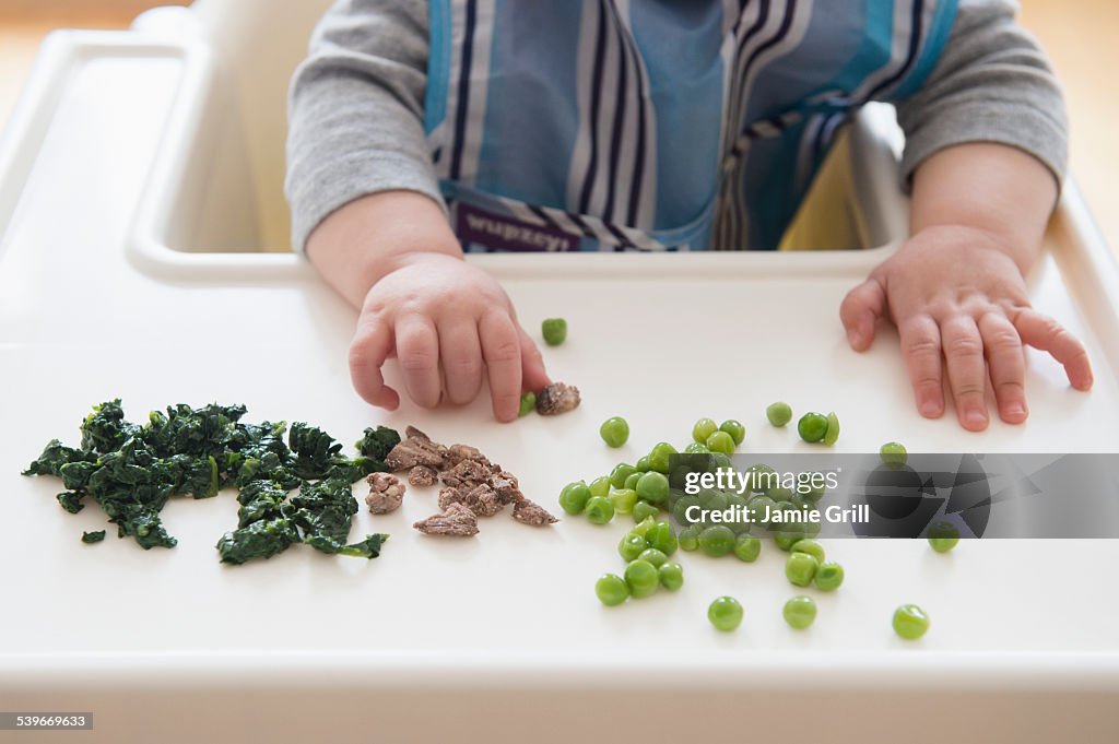 Baby girl (12-17 months) eating steak, spinach and green peas