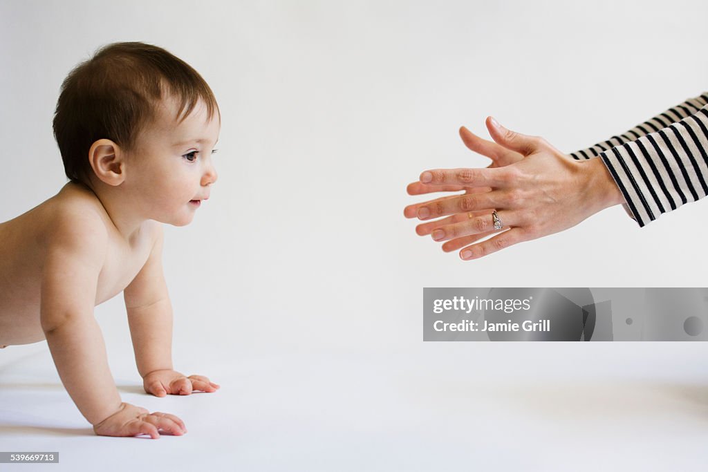 Mother encouraging her daughter (12-17 months) to walk