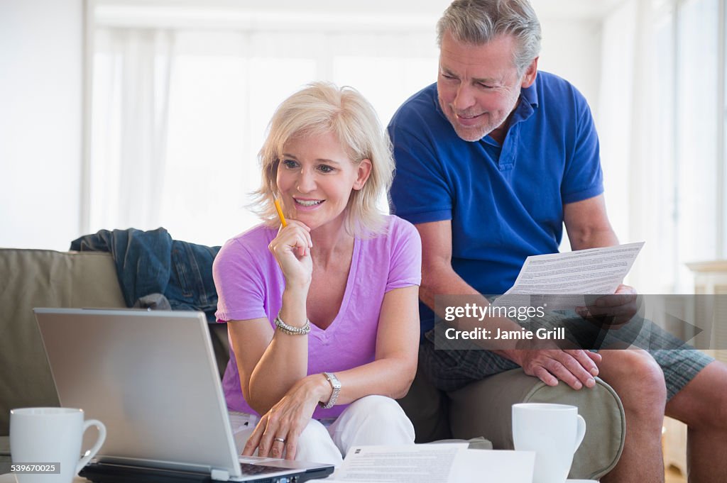 USA, New Jersey, Portrait of couple sitting on sofa using laptop