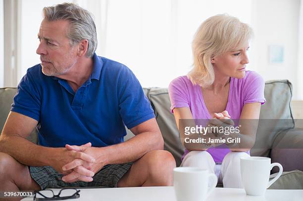 usa, new jersey, portrait of couple sitting on sofa, looking away from each other - ignoring stock-fotos und bilder