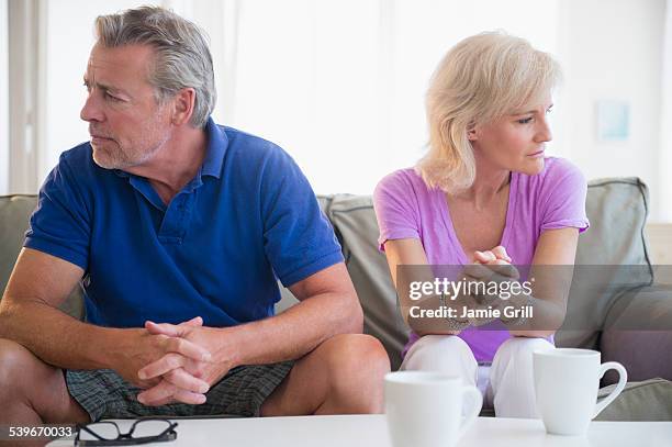 usa, new jersey, portrait of couple sitting on sofa, looking away from each other - unhappy woman blonde glasses stock pictures, royalty-free photos & images