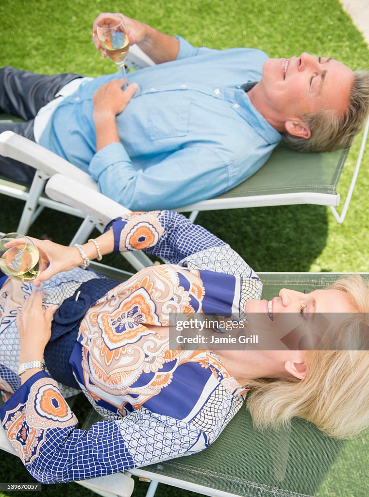 USA, New Jersey, Portrait of couple relaxing on sun loungers on lawn