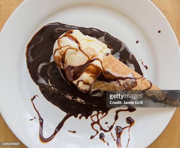 studio shot of ice cream cone on plate with chocolate sauce - chocolate sauce stock pictures, royalty-free photos & images