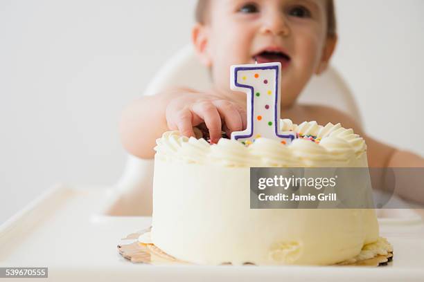 studio shot of baby (12-17 months) reaching for cake - primo compleanno foto e immagini stock