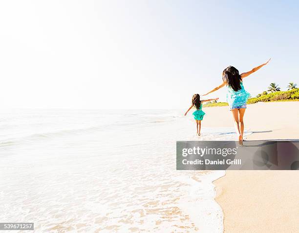 usa, florida, jupiter, rear view of girl (6-7) and her mom running on beach - beach florida family stockfoto's en -beelden