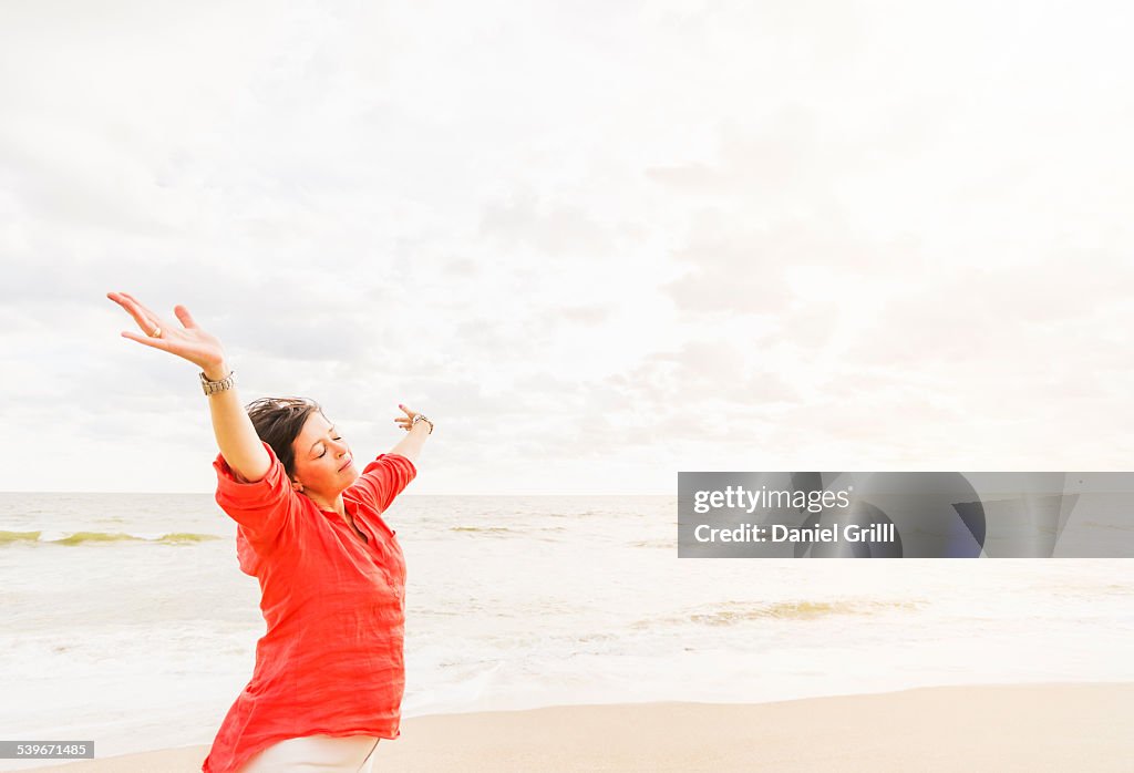 USA, Florida, Jupiter, Side view of woman standing with arms up on beach