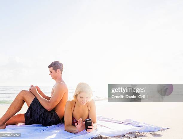 usa, florida, jupiter, portrait of young couple relaxing on beach, using smart phones - ignoring stock pictures, royalty-free photos & images