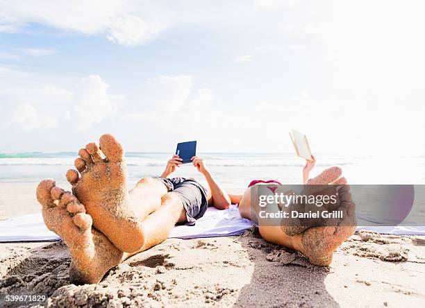 usa, florida, jupiter, close-up of sand-covered feet of young couple lying on blanket on beach reading  - girlfriend feet stock pictures, royalty-free photos & images