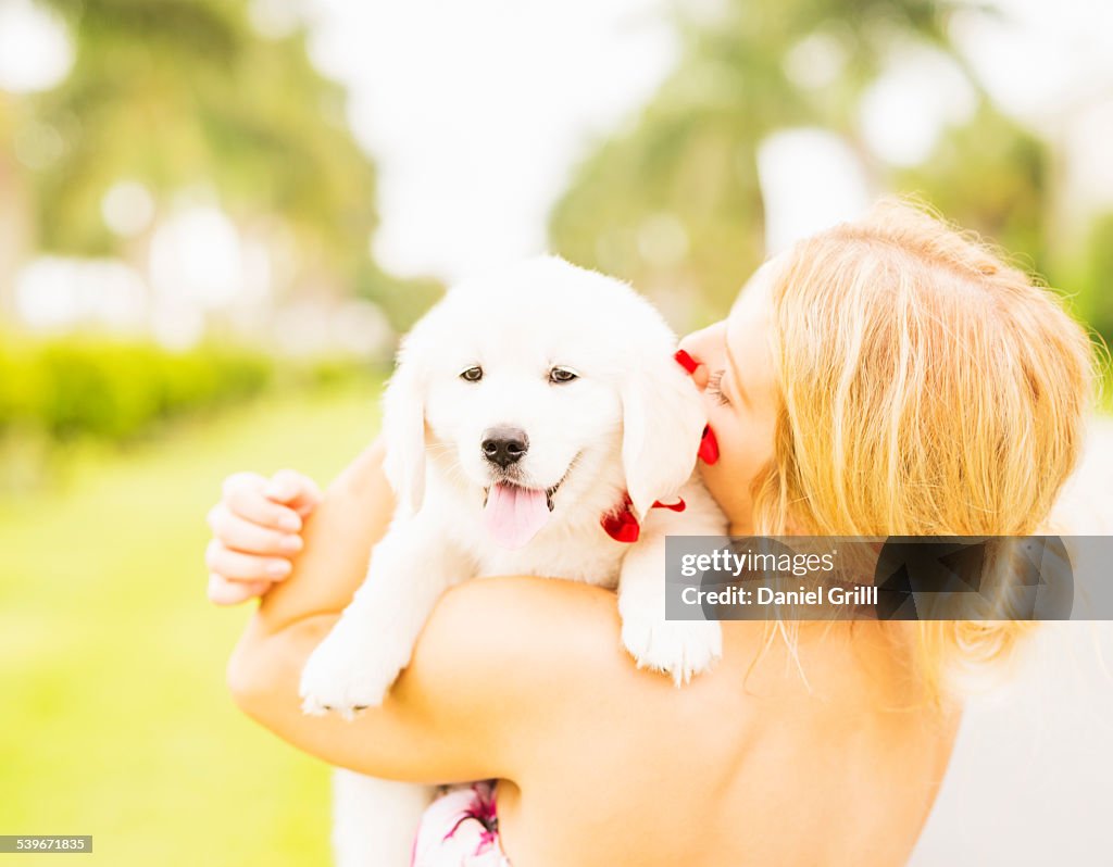 USA, Florida, Jupiter, Close-up shot of young woman embracing white puppy