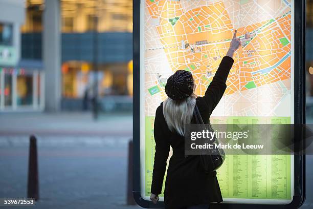 netherlands, tilburg, young woman pointing at city map - city map with points of interest stock pictures, royalty-free photos & images