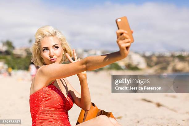 usa, california, costa mesa, blond woman taking selfie on beach - fare il muso foto e immagini stock