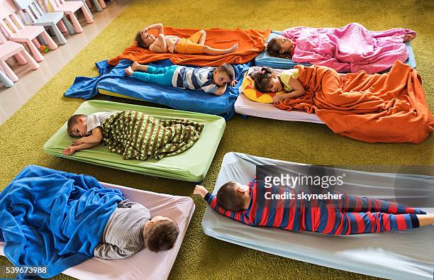 above view of preschoolers in pajamas sleeping at kindergarten. - förskolebyggnad bildbanksfoton och bilder