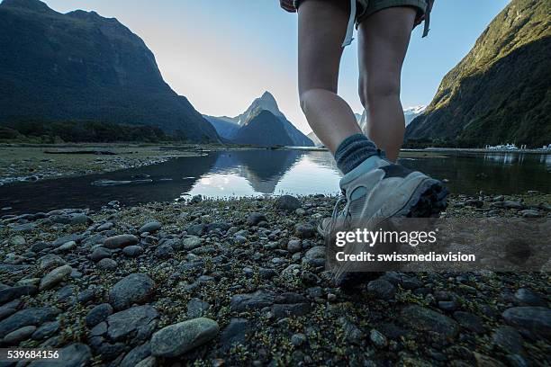woman's legs and hiking boots standing on rocky trail - milford sound stock pictures, royalty-free photos & images