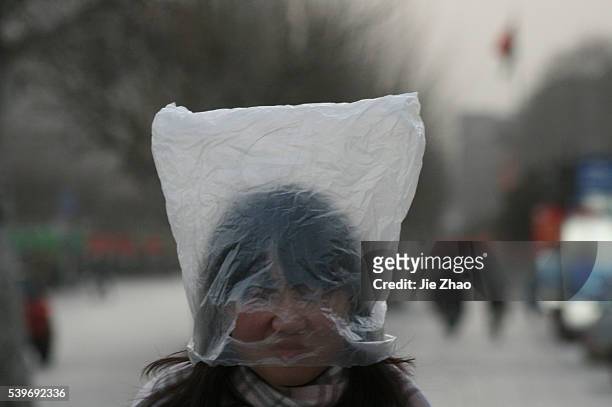 Woman wraps a plastic bag on her head to keep from sand storm in Jinan,Shandong province, March 21,2010.VCP