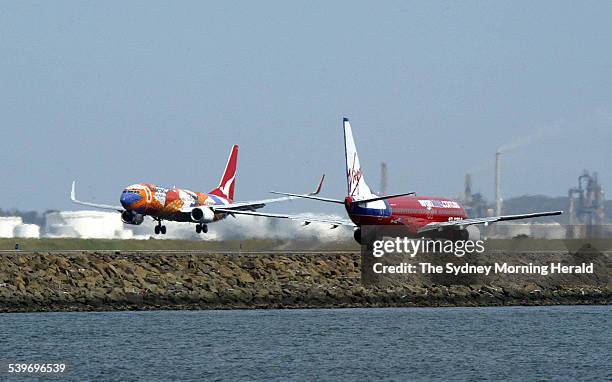 Qantas plane lands as a Virgin Blue plane taxis for take-off at Sydney Airport, 29 November 2004. SMH Picture by ROBERT PEARCE