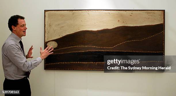 Shaun Dennison with the artwork of Rover Thomas titled Lundari otherwise known as Barramundi Dreaming from the Holmes a Court Collection hung at...