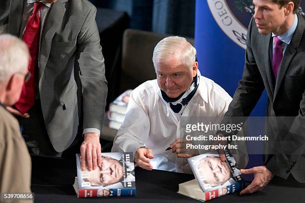 Former Defense Secretary Robert Gates signs books after talking about his new book, "Duty" that criticizes many Bush and Obama administration...