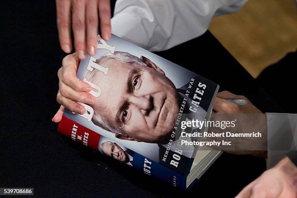 Former Defense Secretary Robert Gates signs books after talking about his new book, "Duty" that criticizes many Bush and Obama administration...