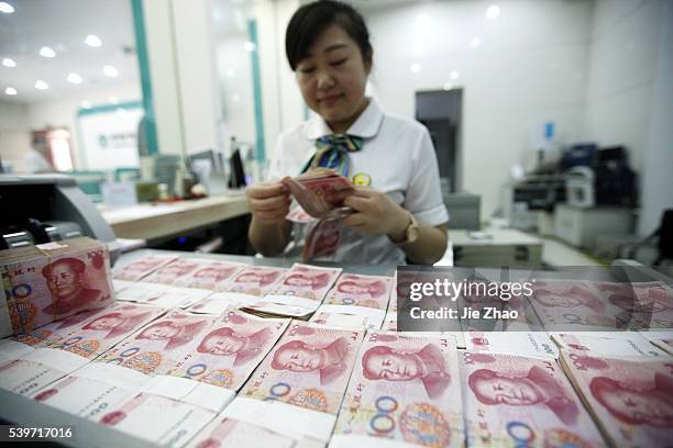 Worker counts Chinese currency Renminbi at a bank in Hauibei, east China's Anhui Province, Aug 26, 2015. China's yuan fell against the dollar on...
