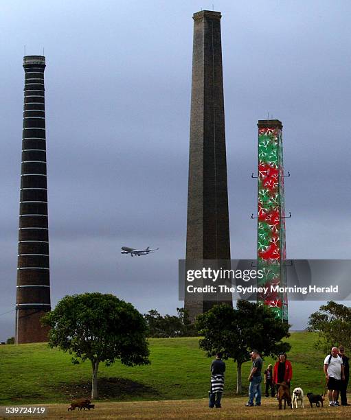 People play with their dogs in Sydney Park where two of the four chimneys of the old brickworks have been decorated with colourful banners, 30...