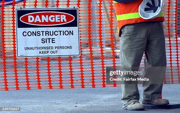 Building worker holding his hard hat on a construction site, beside a warning sign reading 'Danger Construction Site', 2 September 2003. AFR Picture...