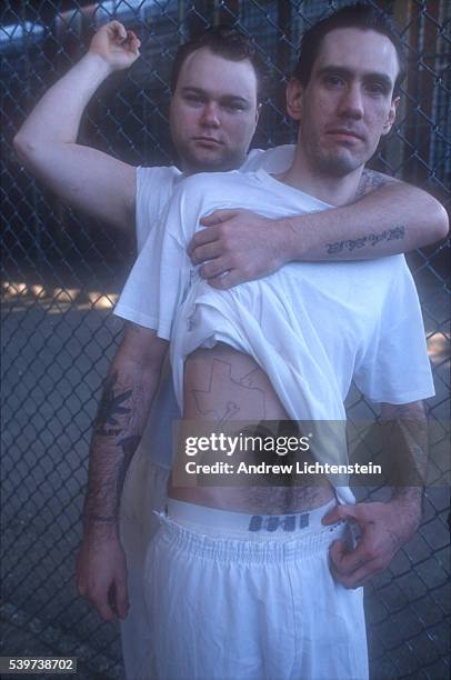 Two members of the Texas branch of the Aryan Nation prison gang relax in a yard that seperates them from rival gang members. As confirmed members of...