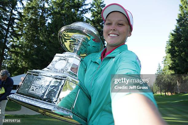 Brooke Henderson of Canada poses for a simulated selfie with the trophy after winning the KPMG Women's PGA Championship in a playoff against Lydia Ko...