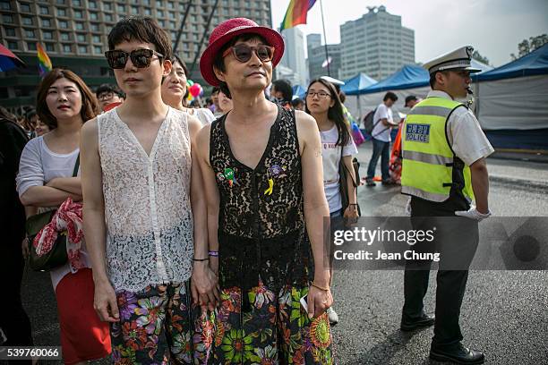 Kim Seung-Hwan and his partner, Kim Jho Gwang-Soo walk past a policeman during the Queer Festival on June 11, 2016 in Seoul, South Korea. While the...